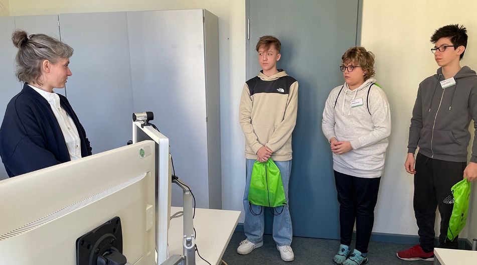 Drei Jungen des Boys'Day 2025 hören im Ministerium für Bildung und Kindertagesförderung im Büro einer Referentin aufmerksam zu.